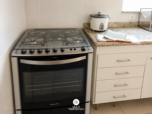 A kitchen with a stove, oven, and a slow cooker on the countertop.