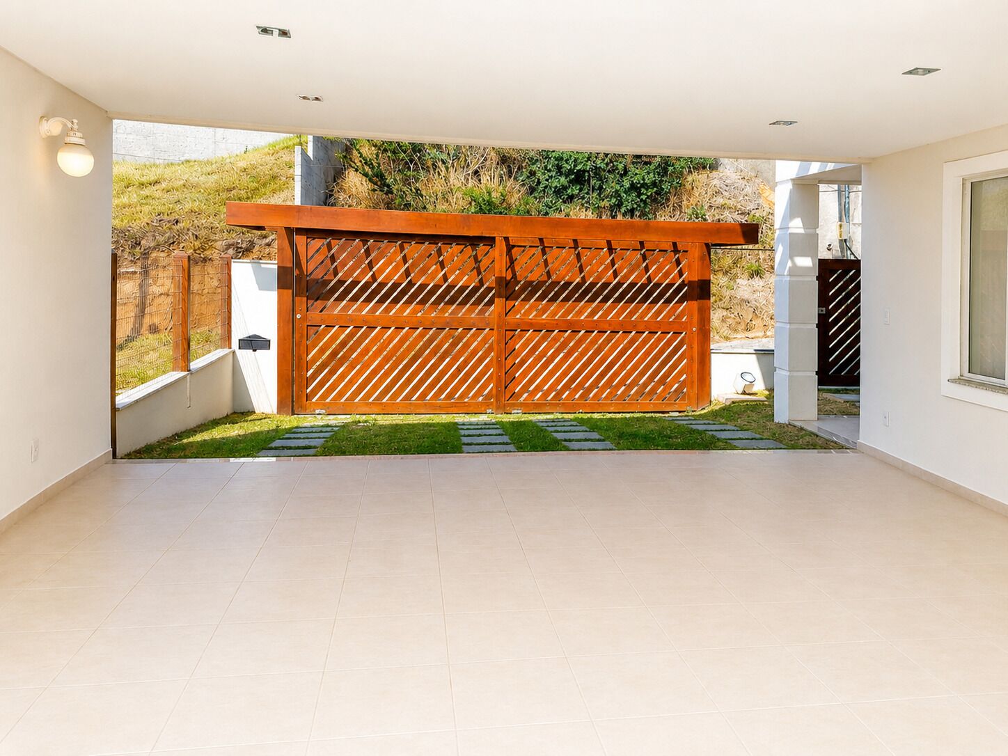 Une pièce moderne dotée d’une grande fenêtre, d’une porte en bois et d’un sol carrelé.