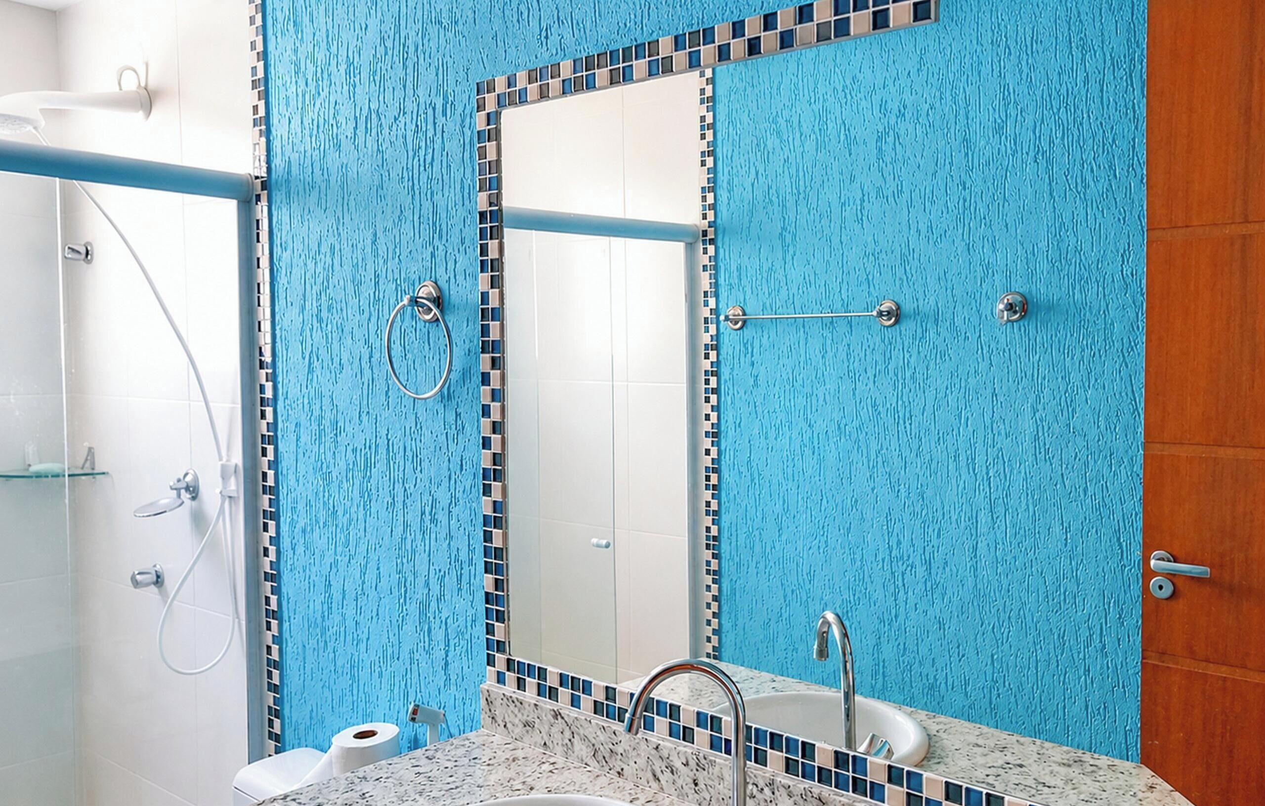 Un baño con pared azul texturizada, un espejo, un lavabo y una ducha.