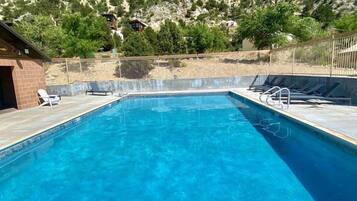 A rectangular swimming pool with clear blue water, surrounded by a tiled deck.