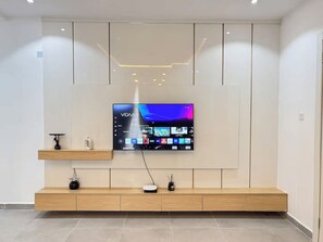 A modern living room with a mounted flat-screen TV, wooden console, and a minimalist design. - Radiant 1-Bedroom in Victoria Island with Pool, Fast Wi-Fi & 24/7 Power (Lagos)