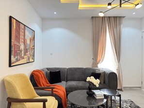 Ein modernes Wohnzimmer mit einem grauen Sofa, einem gelben Sessel, einem Couchtisch und einem Gemälde an der Wand.