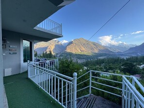 A balcony with a view of mountains and a river. - Altitude 7788, 
Scenic 2-Bedroom Apartment in the Heart of Karimabad (Karimabad)