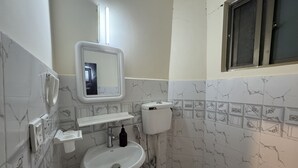 Een kleine badkamer met een wit wastafelmeubel, toilet en een spiegel erboven.