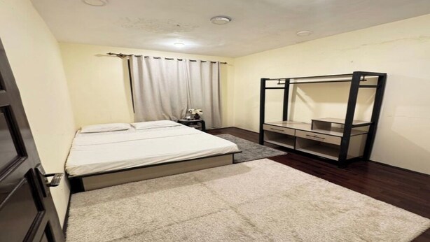 Een slaapkamer met een bed, nachtkastje, spiegel en kledingkast.
