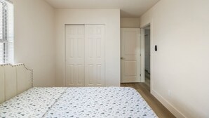 A bedroom with a bed, a door, and a window with blinds.