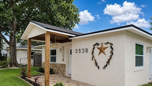 A single-story house with a stone foundation, a covered porch, and a number '5538' on the wall.