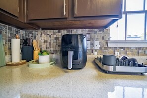 A kitchen with a coffee maker, utensils, and a plant on the counter.