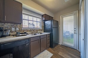 A kitchen with a dishwasher, stove, sink, and a refrigerator.