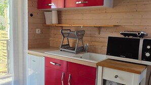 A compact kitchen with red cabinets, a microwave, and a coffee maker.