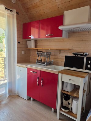 A compact kitchen with red cabinets, a microwave, and a coffee maker. - Ailéa – Tiny House with a Private Hot Tub in Provence (Beaumes-de-Venise)