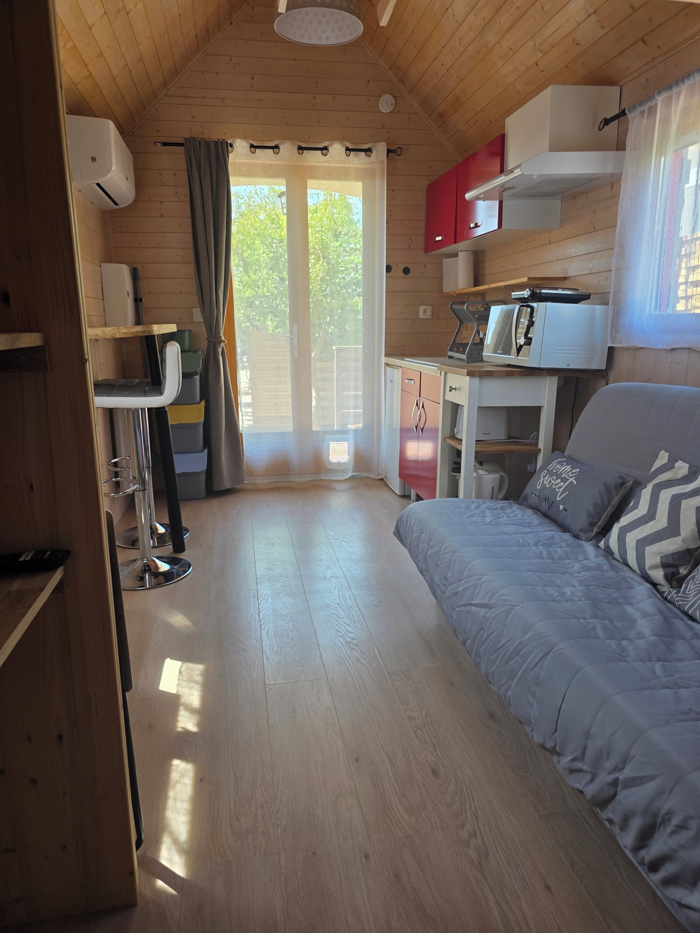 Een knus ingerichte kamer met een bed, bureau en kitchenette.