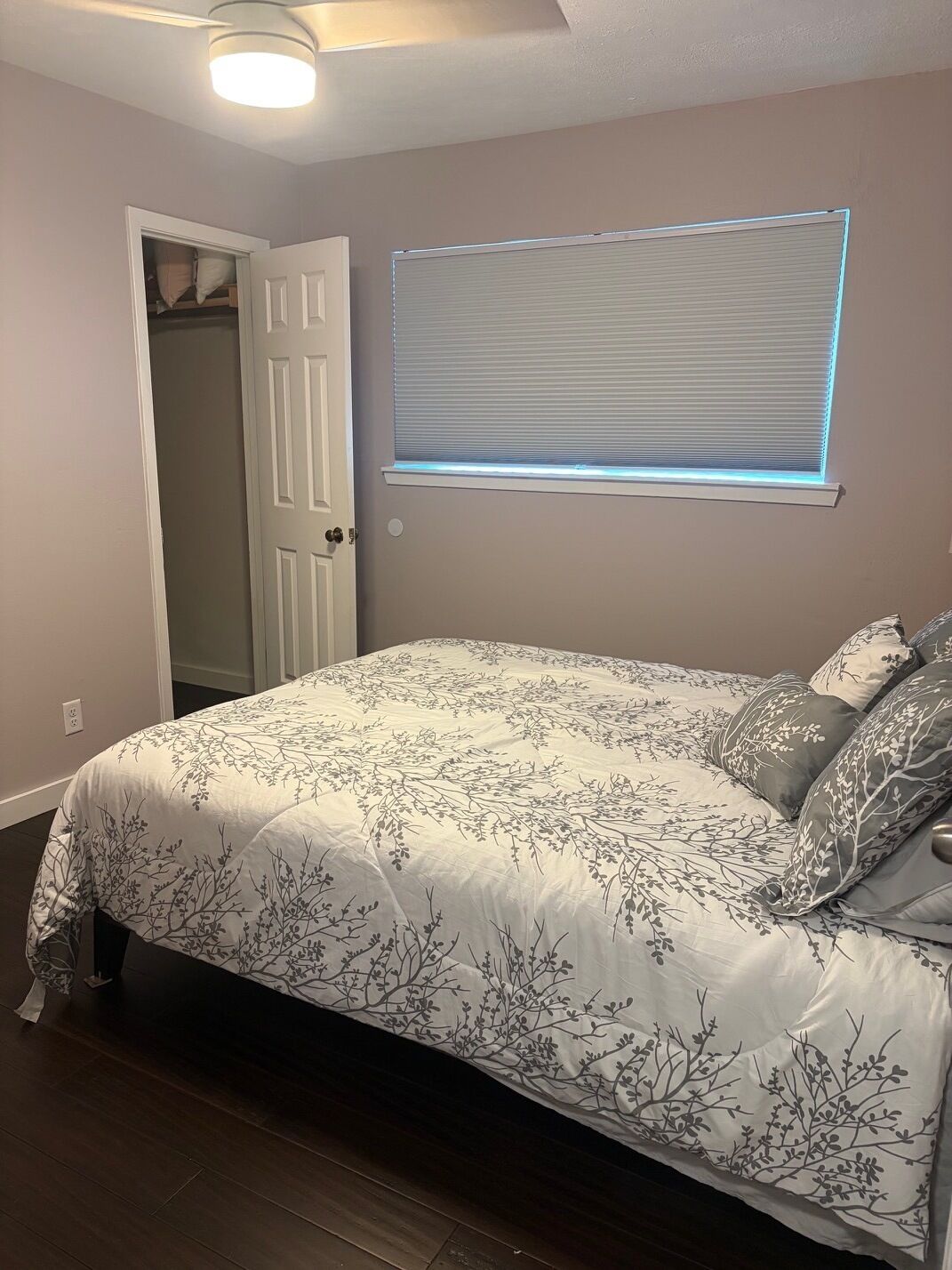 Quarto com cama, armário e janela com persianas.