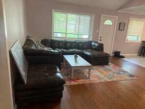 A living room with a sectional sofa, a coffee table, and a patterned rug.