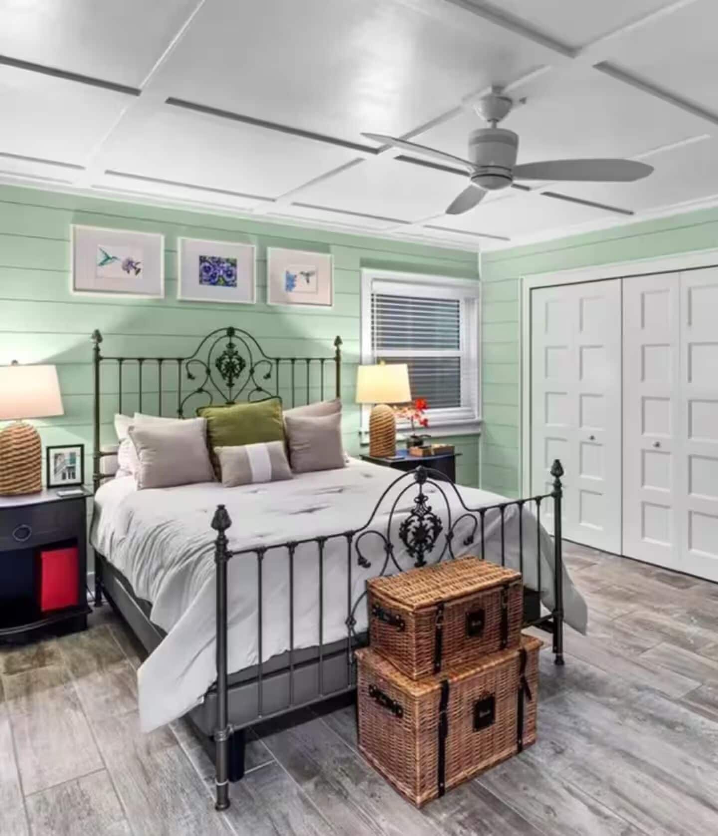 Une chambre à coucher avec un lit, un ventilateur de plafond, une fenêtre avec des stores et une porte.
