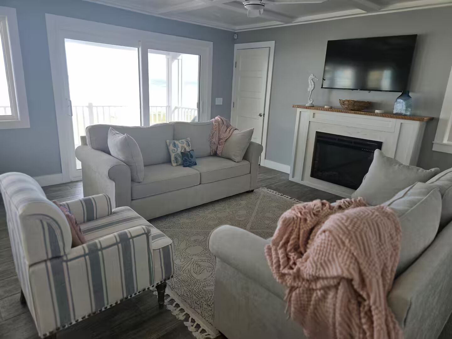 A living room with a sofa, a striped armchair, a fireplace, and a television.