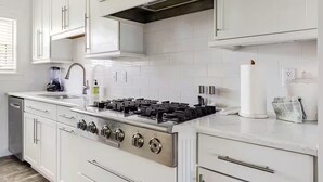 Eine moderne Küche mit weißen Schränken, einem Edelstahlherd und einem eingebauten Backofen.