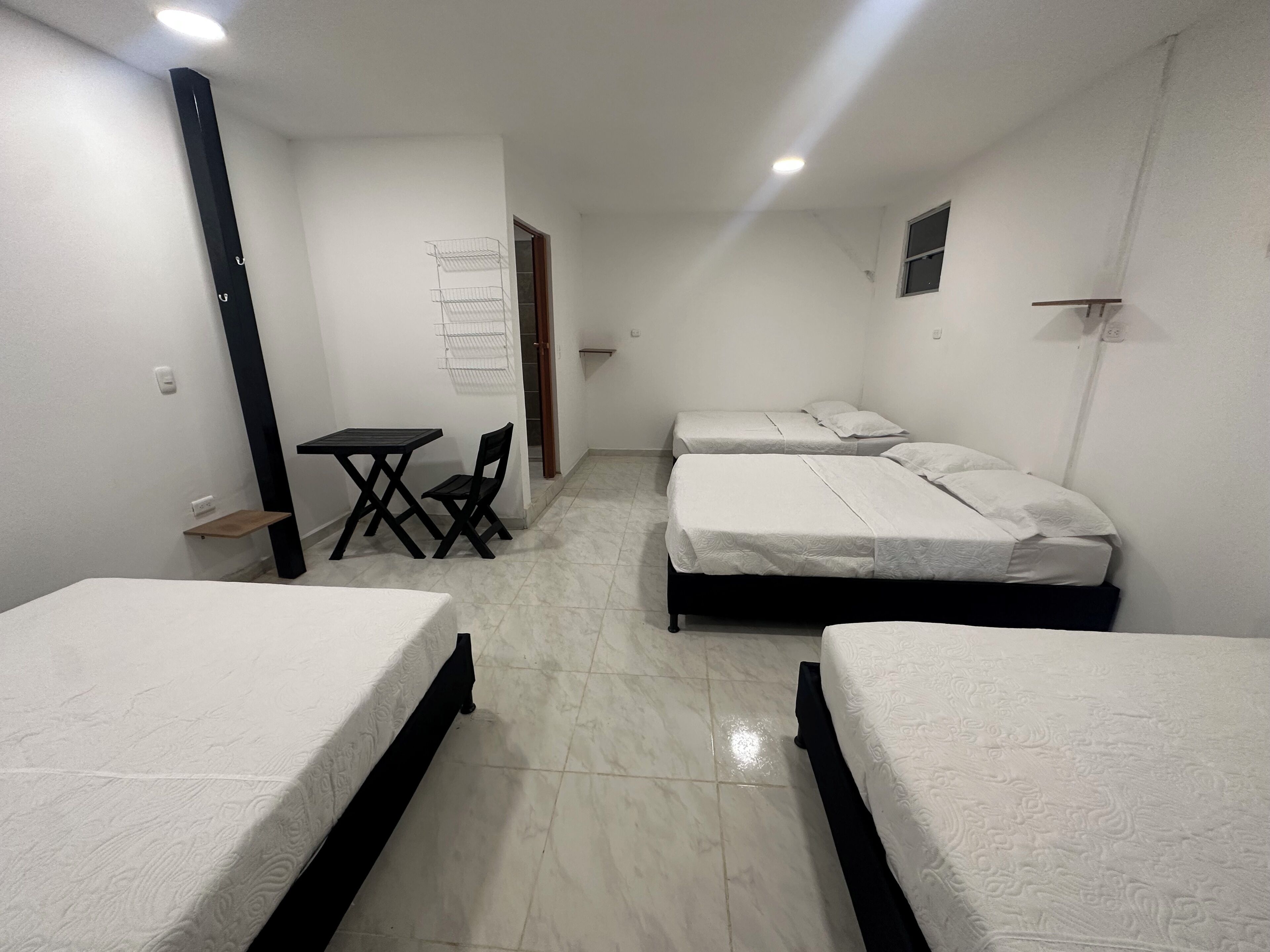 A room with three beds, a small table, and a chair.