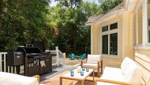 A patio with outdoor furniture, a grill, and a deck with a railing. - The Grand Carolina | Golf Cart ·Hot Tub ·4BR ·PKS (Pine Knoll Shores)
