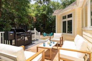 Eine Terrasse mit Gartenmöbeln, einem Grill und einem Deck mit Geländer.