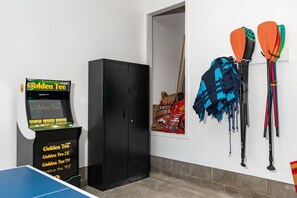 Et værelse med et ping pong bord, et skab og udstyr til paddleboard.