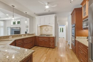 Eine moderne Küche mit Granit-Arbeitsplatten, Holzschränken, einem eingebauten Backofen und einem Deckenventilator.