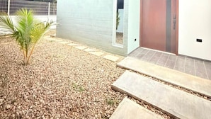 A modern building with a flat roof, a single visible door, and a small palm tree in the foreground.