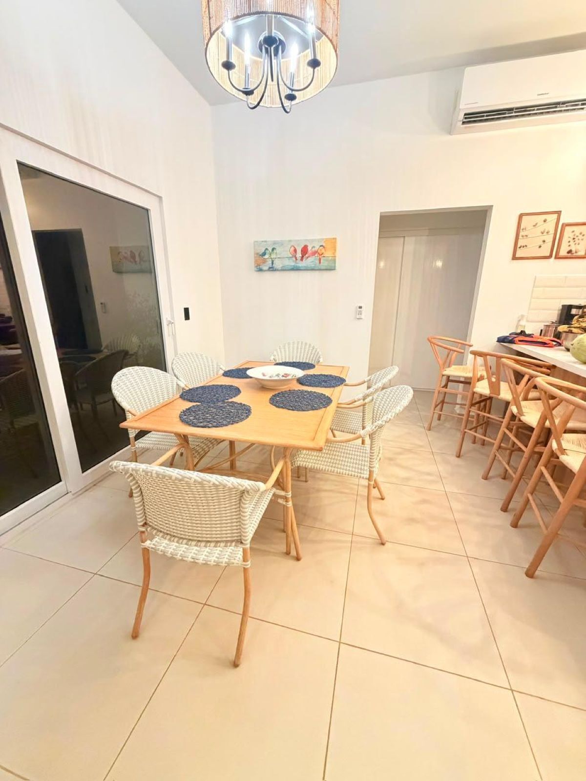 Comedor con mesa y sillas, una araña y un puerta corrediza de vidrio.