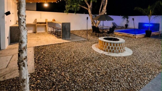 An outdoor patio area with a fire pit, seating, and a pool.