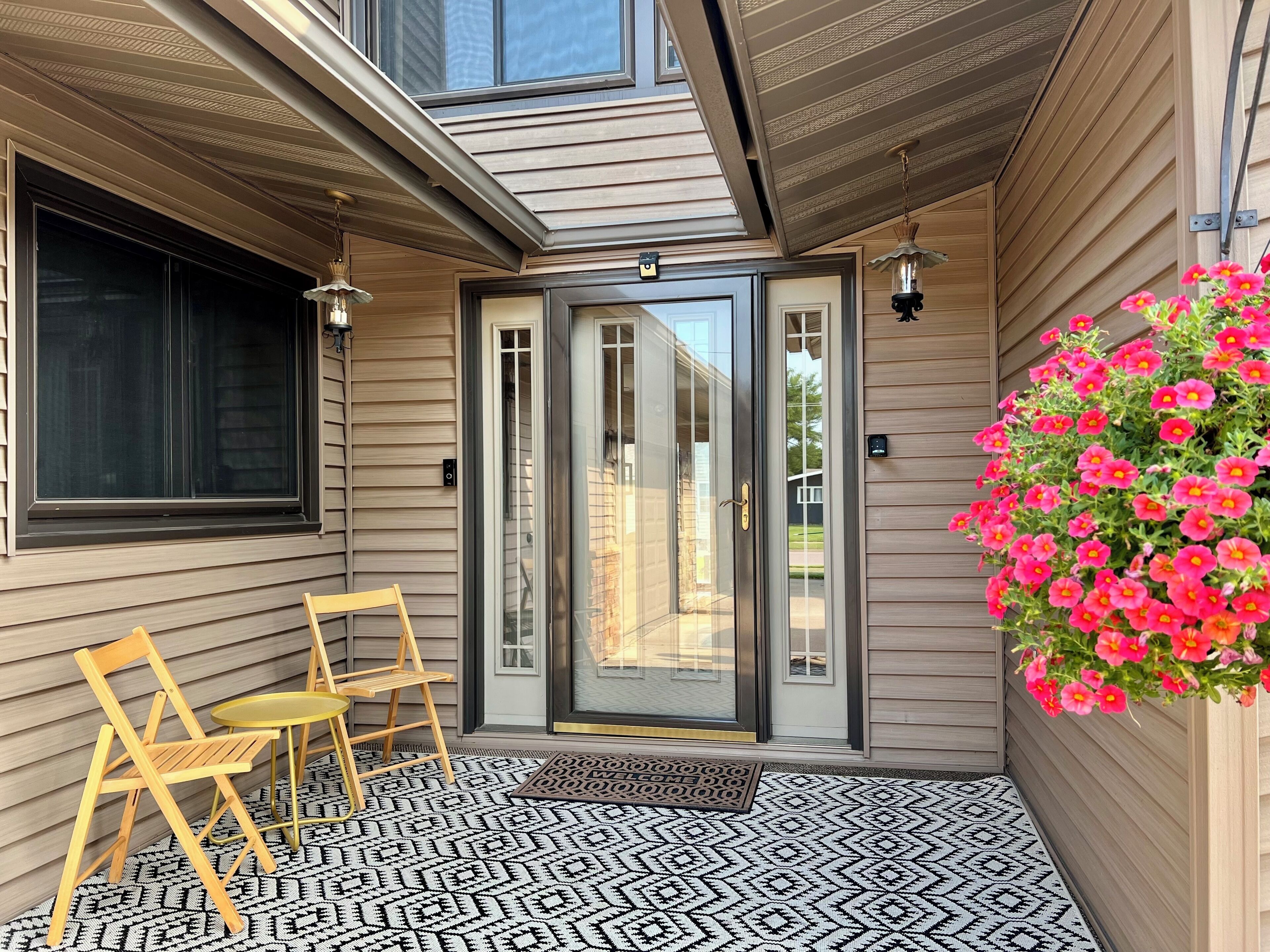 A covered porch with a sliding glass door, a small table with chairs, and a patterned rug.