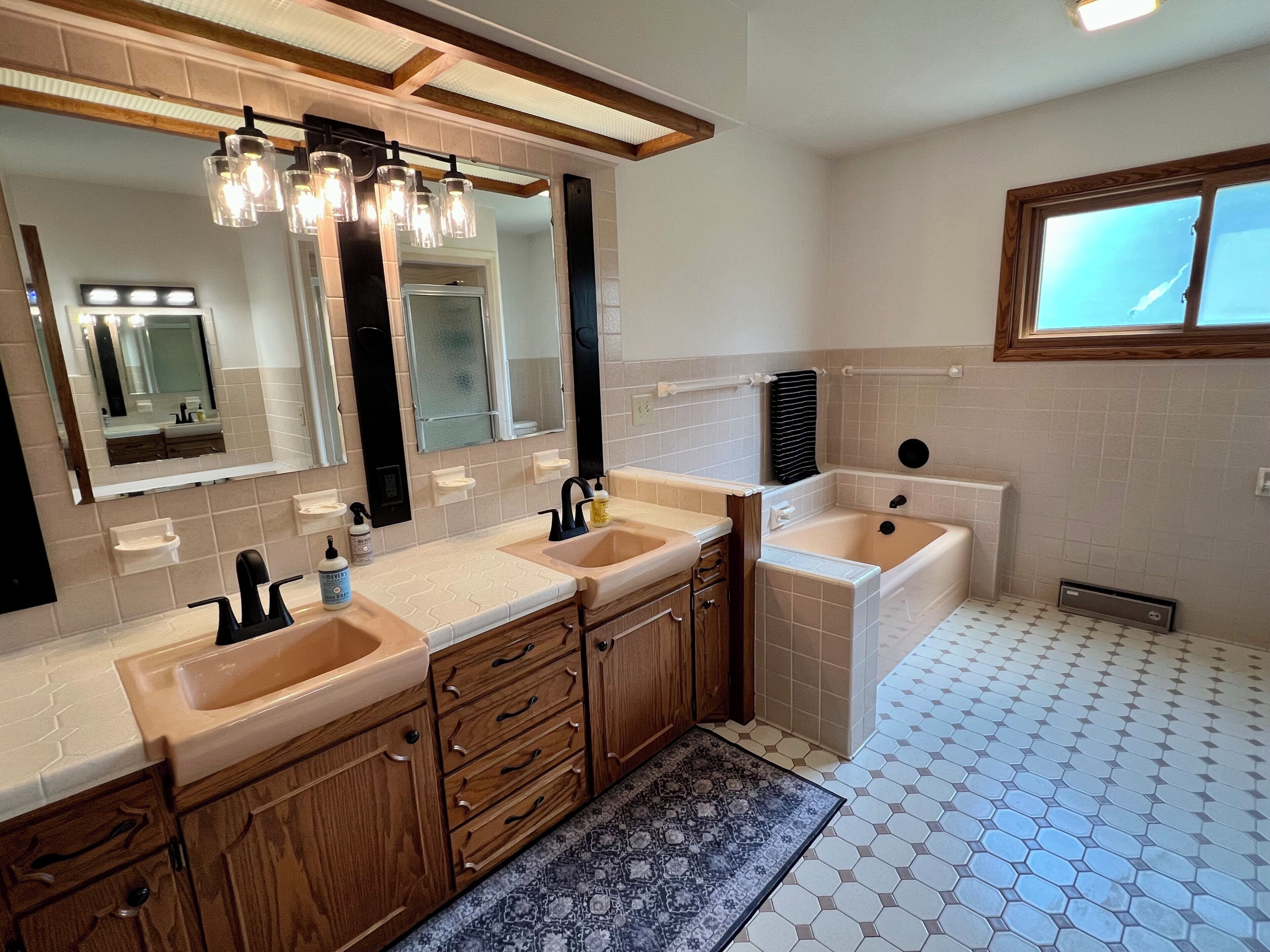 Un bagno moderno con un doppio lavabo, una vasca e uno specchio grande.