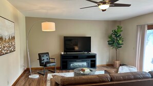 A modern living room with a flat-screen TV, leather sofa, floor lamp, and a ceiling fan. - Spacious Independence Home - Conveniently Located (Independence)