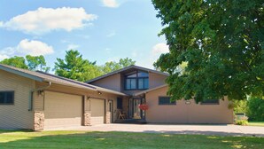 A two-story house with a garage, a front porch with a flower planter, and a well-maintained lawn. - Spacious Independence Home - Conveniently Located (Independence)