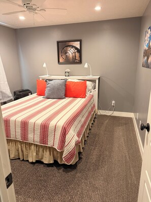 A bedroom with a bed, a ceiling fan, a nightstand, a lamp, a picture on the wall, and a carpeted floor. - Quiet 2 Bedroom 1 Bath in Payson, UT (Payson)
