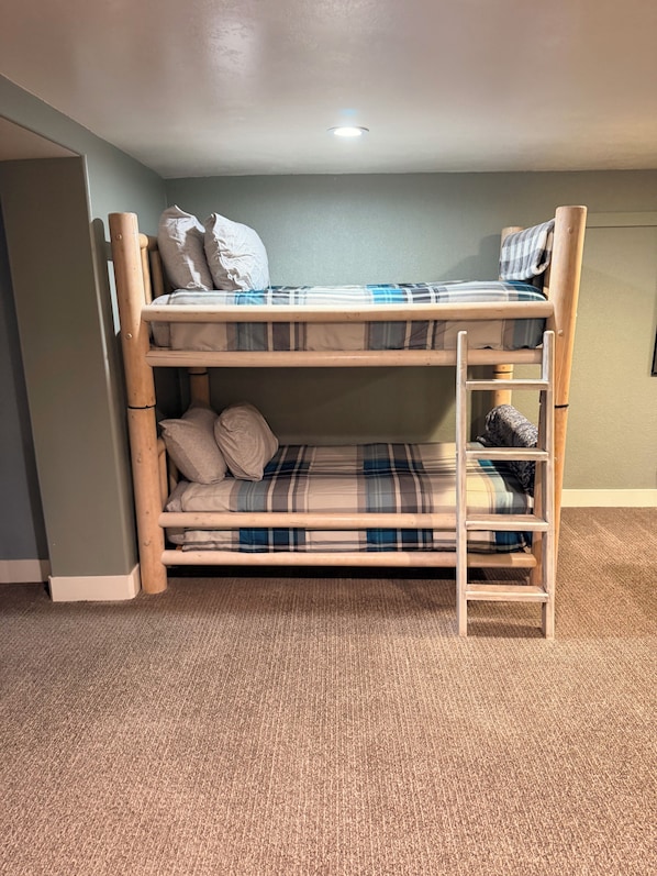 A bunk bed with a ladder, pillows, and a plaid blanket.