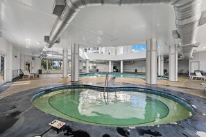 Ein Schwimmbeckenbereich mit Hinweisschild für eine maximale Wassertiefe von 90 Zentimetern, umgeben von weißen Säulen und einer überdachten Konstruktion.