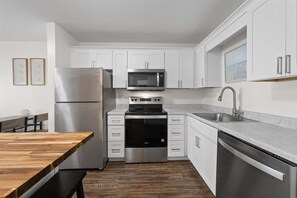 Una cocina moderna con armarios blancos, electrodomésticos de acero inoxidable y una mesa de comedor de madera.