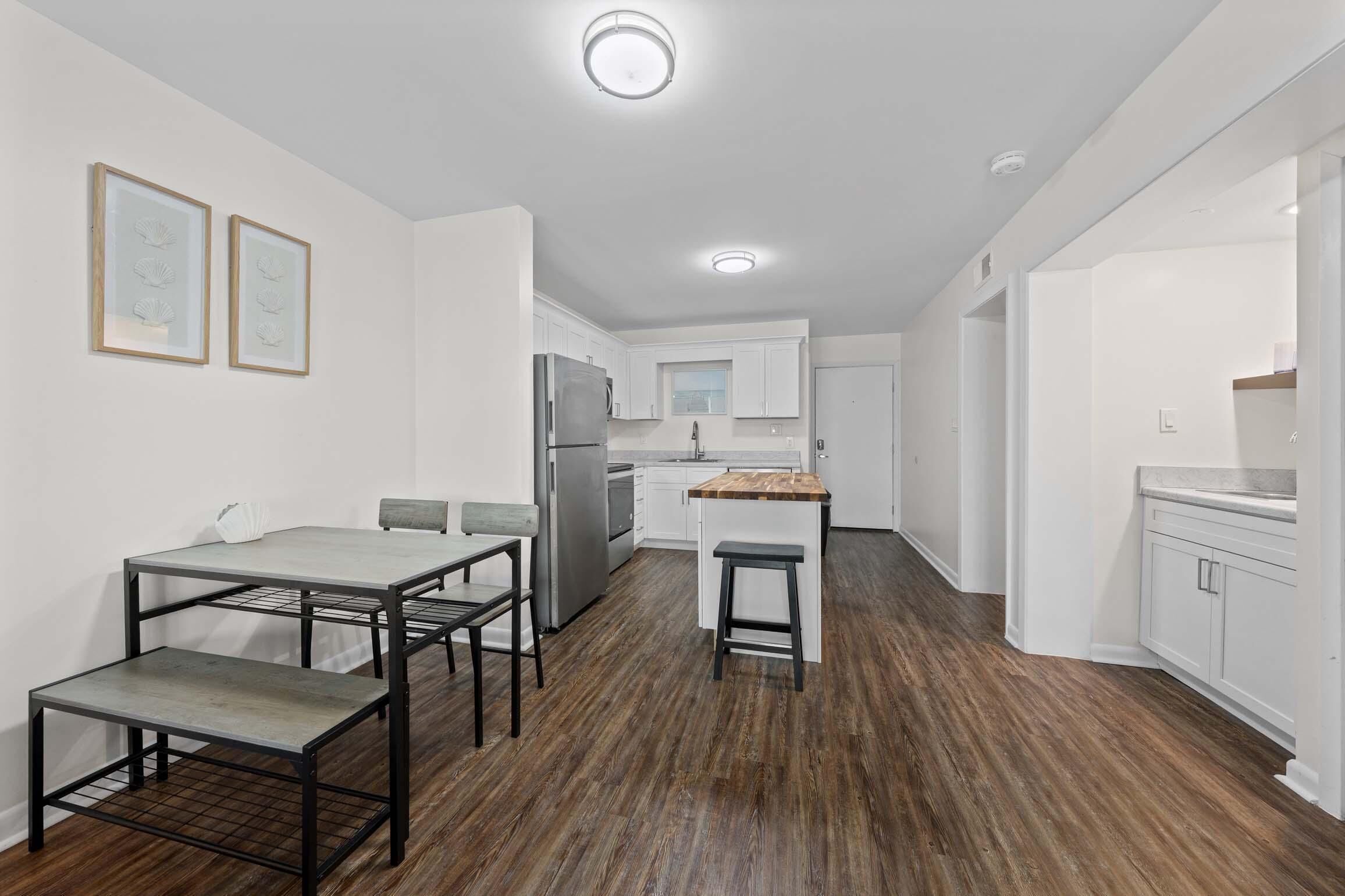 A modern kitchen with white cabinets, a stainless steel refrigerator, and a wooden countertop.