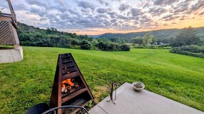 Un cortile con una griglia per barbecue, un tavolo in cemento e una ciotola di carbone.