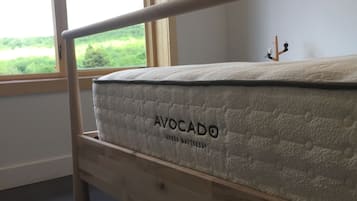 Un lit superposé avec un matelas portant l’étiquette « MATELAS VERT AVOCAT » dans une pièce dotée d’une grande fenêtre.