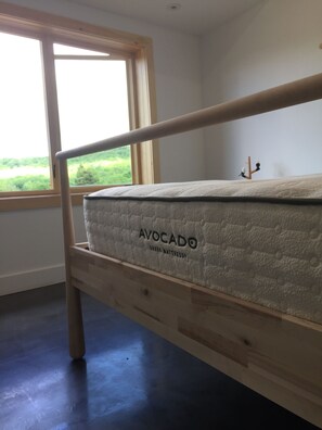 Un letto a castello con un materasso etichettato 'AVOCADO GREEN MATTRESS' in una stanza con una grande finestra.