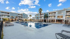 Un hotel con piscina, diversi balconi e cielo sereno.