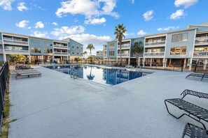 A hotel with a swimming pool, multiple balconies, and a clear sky. - Sea Oats A102 by ALBVR - Lagoon Front Updgraded Condo (Gulf Shores)