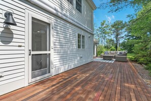 A deck with outdoor furniture and a house with white siding. - Luxury property with relaxing backyard and with walking distance from the Gooch’s Beach ( Kennebunk)  and Dock Square in Kennebunkport. First floor King size bed and en suite ( shower only ) bathroom. Two living rooms and relaxing back yard deck. (Kennebunk)