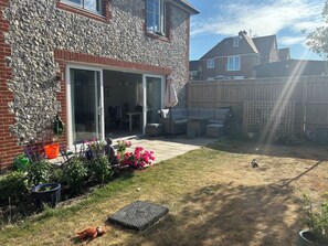 Patio trasero residencial con mobiliario exterior y diversas plantas.