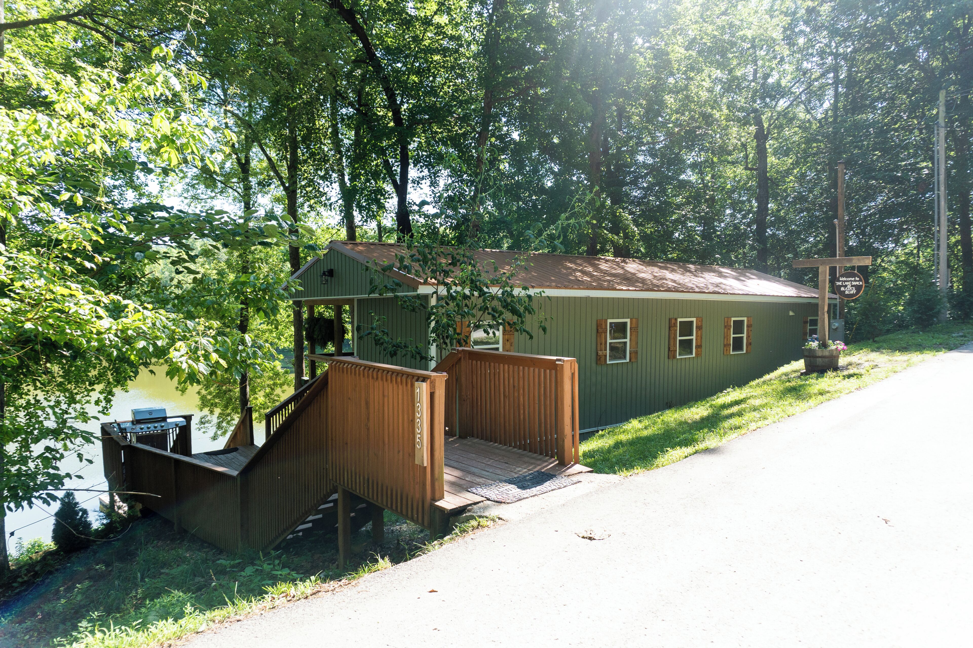 A cabin with a wooden deck and a small porch, surrounded by trees.
