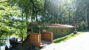 A cabin with a wooden deck and a small porch, surrounded by trees.