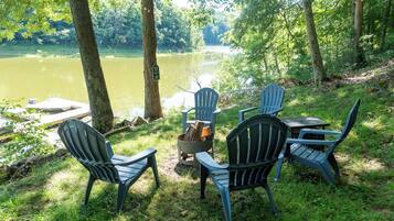 Un espace aménagé au bord du lac, avec des fauteuils Adirondack et un foyer.