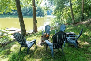 Un espace aménagé au bord du lac, avec des fauteuils Adirondack et un foyer.