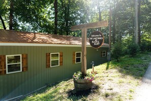 A wooden sign with text welcoming visitors to a location named 'The Lake Shack at Blair's Bluff.'